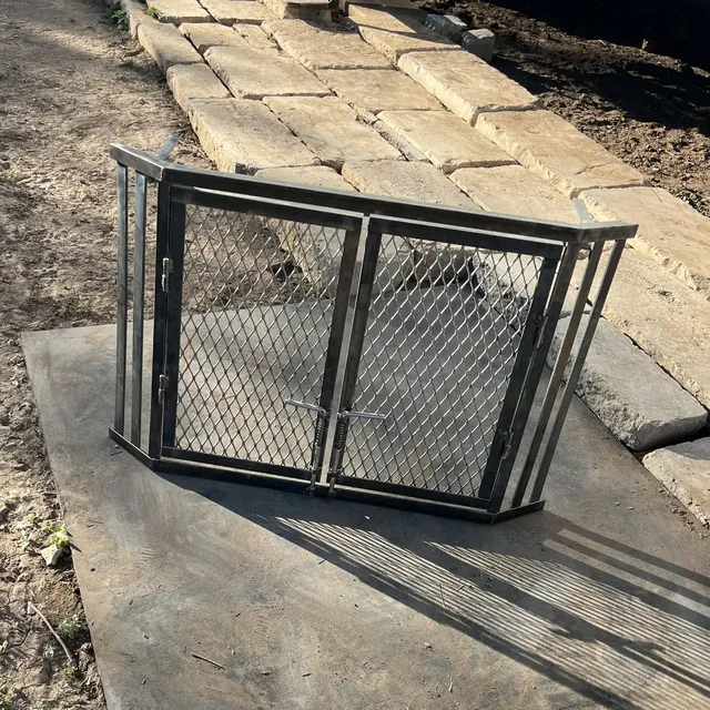 A black steel diamond-mesh screen with a two-door front, set on a stone floor
