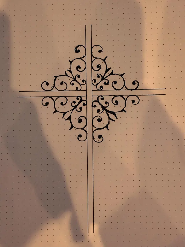 A scrolled iron cross design laid out flat on a pegboard in black steel before welding