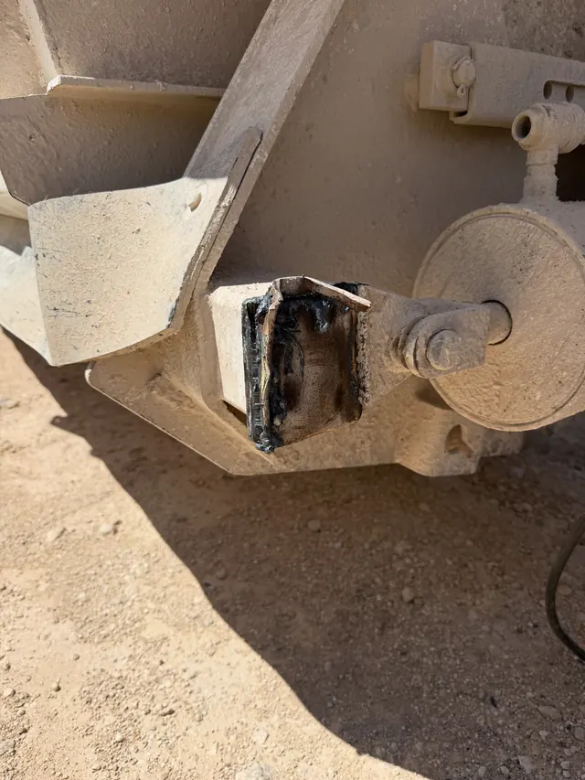 A close view of a trailer frame where a broken jack mount has been cut away, ready for the new weld