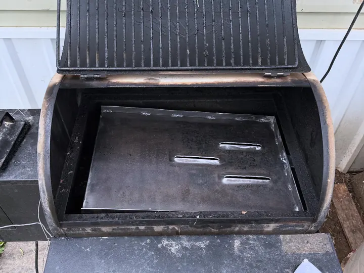 A new heavy-gauge steel catch pan with slotted vents fitted inside the barrel of a smoker grill
